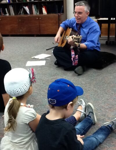 Andrew Walker playing the guitar for some children